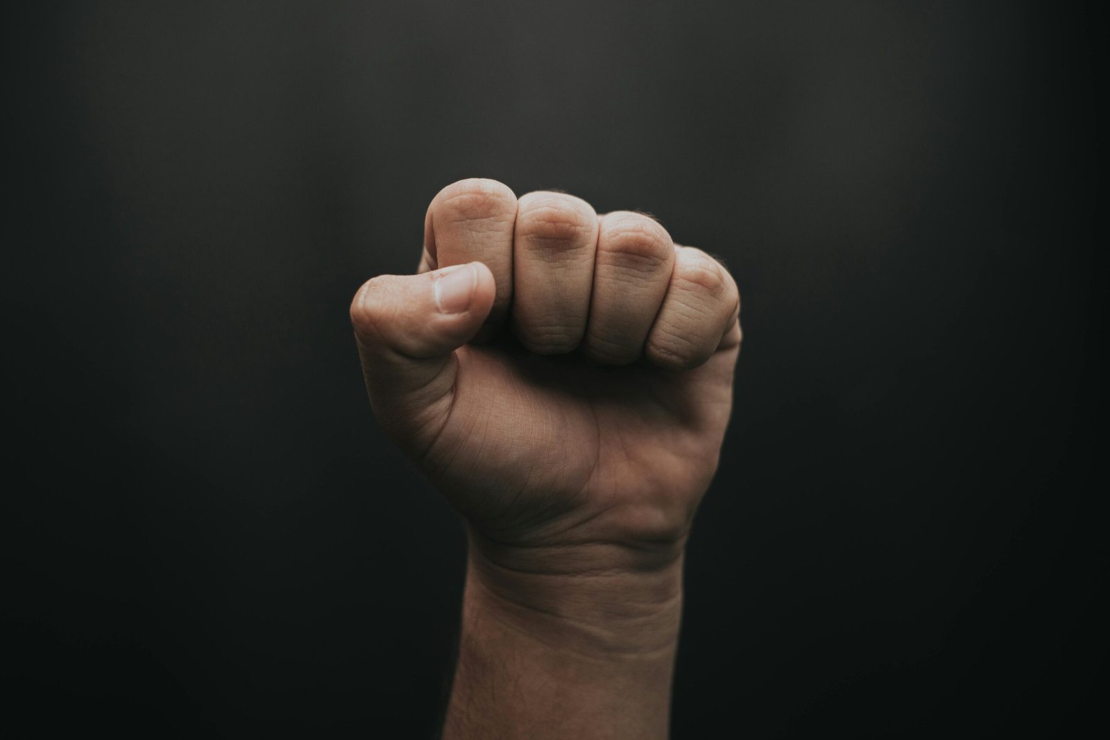 Raised fist symbolizing Courage Character Strengths against a blurred dark background
